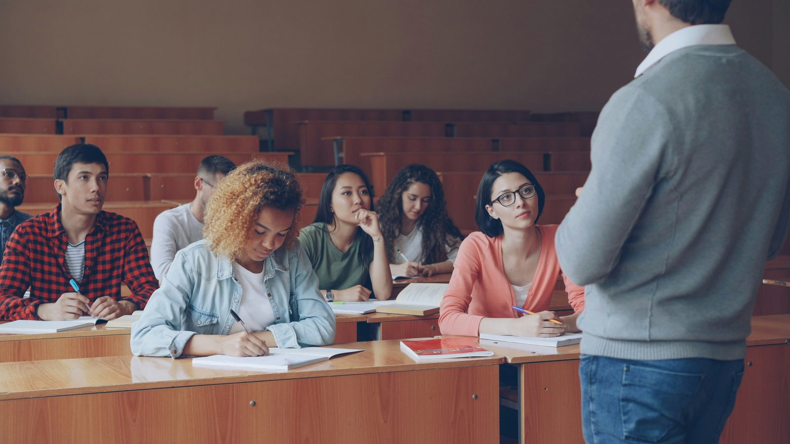 A lecturer addressing students taking notes in a university lecture hall